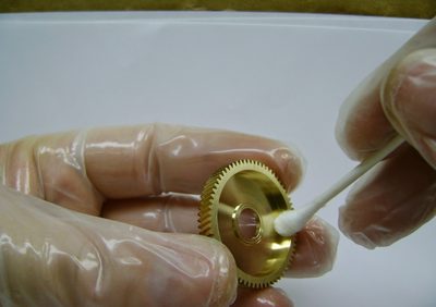 Hand-detailing a brass reel gear with a cotton swab